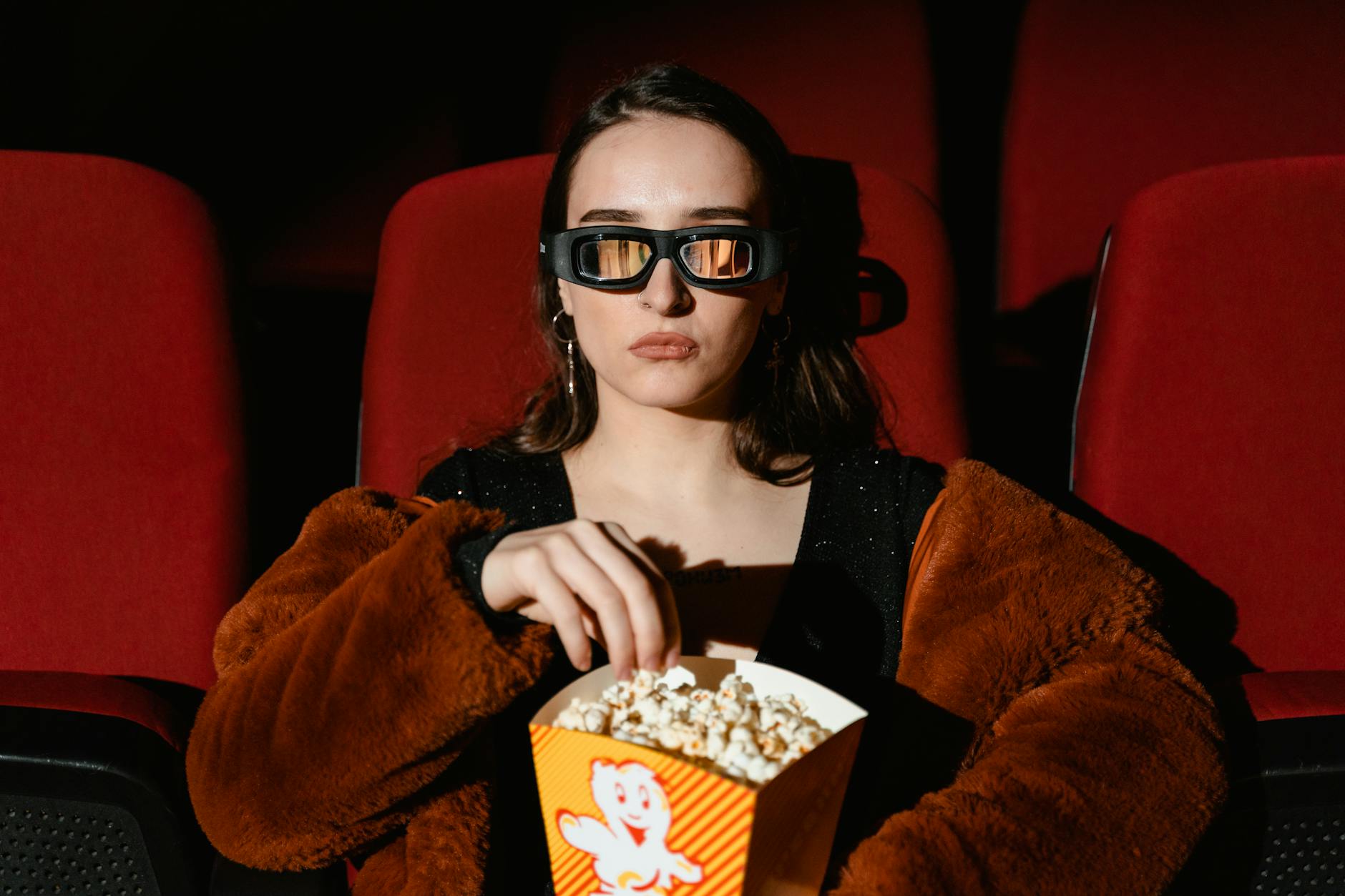 woman watching a movie holding a box of popcorn