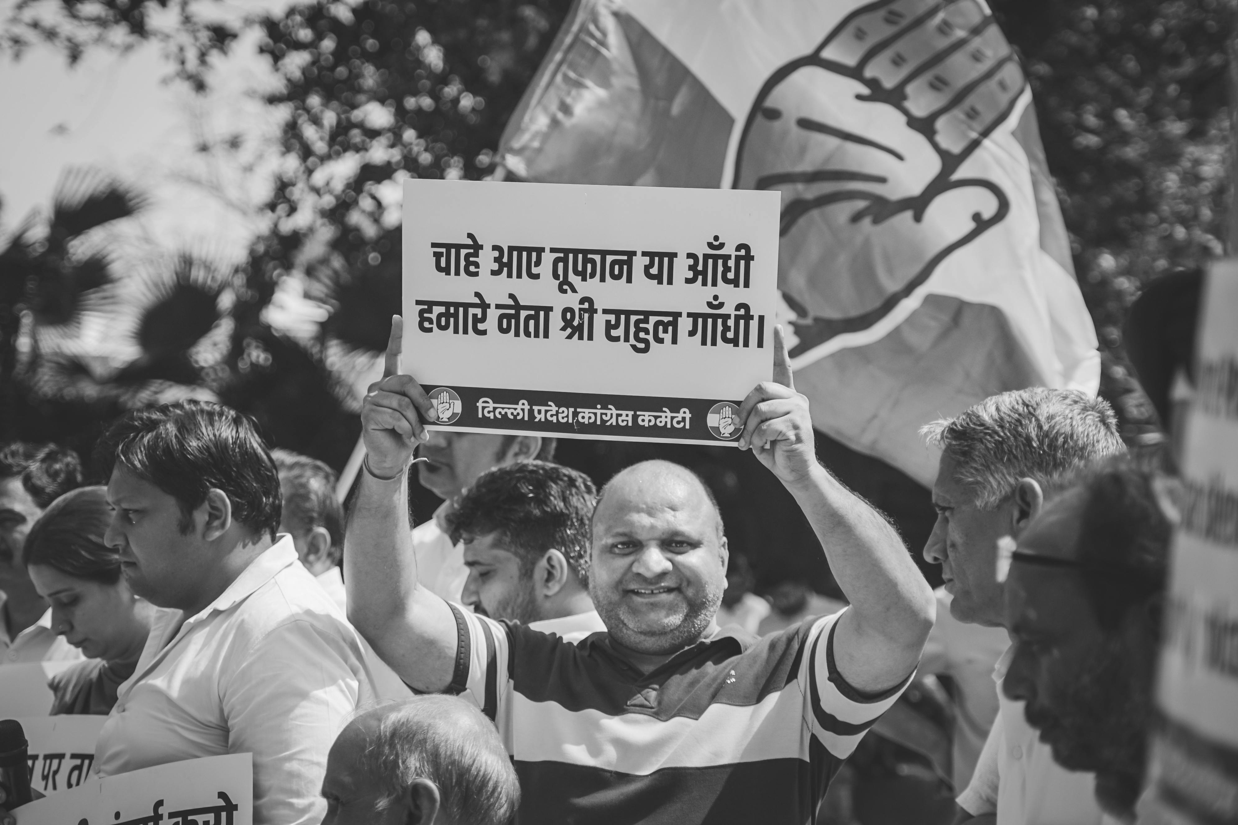 Protesters holding a placard praising a political leader during a public demonstration in India, illustrating how political narratives gain visibility through mass participation